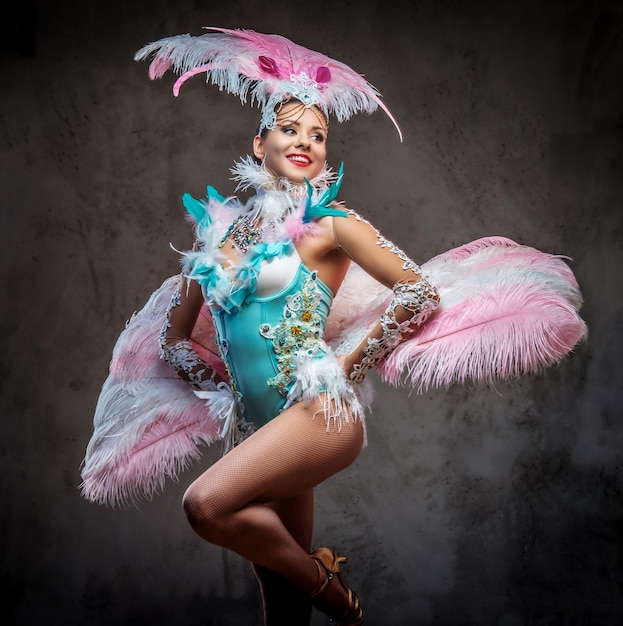 Beautiful girl in a sumptuous carnival feather suit. Isolated on a dark background.