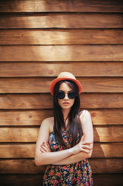Beautiful girl in sunglasses posing on brown wall
