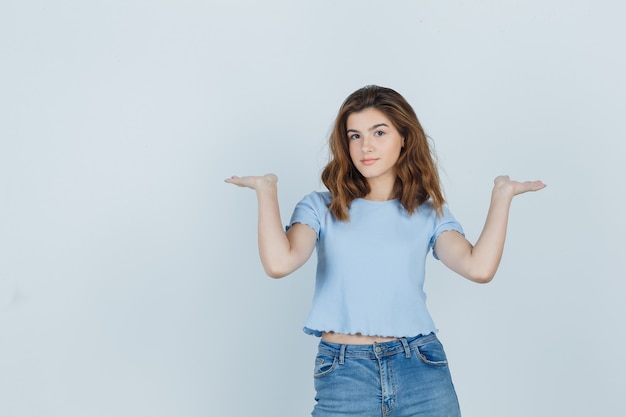 Beautiful girl in t-shirt, jeans showing welcome gesture and looking kind , front view.