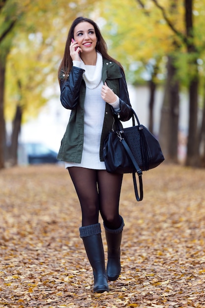 Beautiful girl talking on phone in autumn.