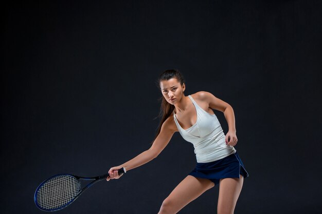 暗い背景にラケットで美しい少女テニスプレーヤー