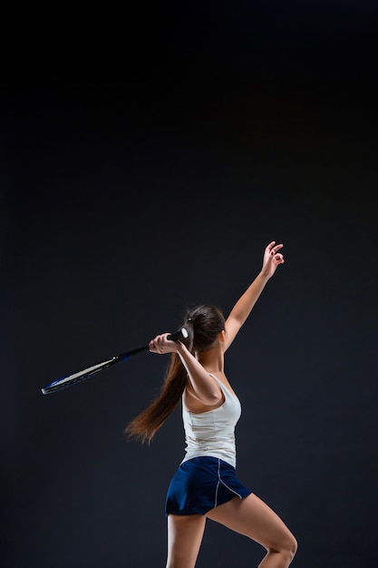 Foto gratuita tennista bella ragazza con una racchetta su sfondo scuro