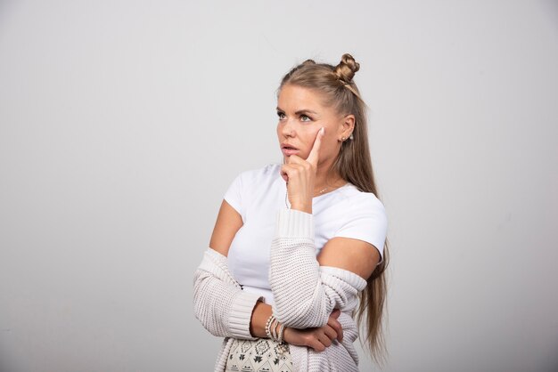 Beautiful girl thinking about something on gray background.