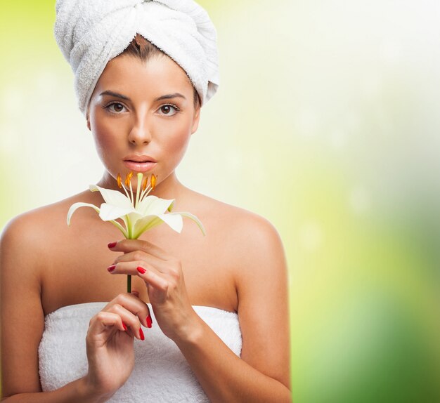 Beautiful girl in towel holding white lily