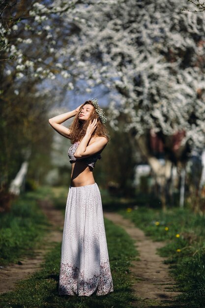 花輪に身を包んだ緑豊かな庭園を歩く美少女