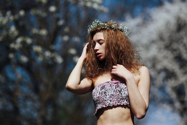 Beautiful girl walks in the lush garden dressed in a wreath