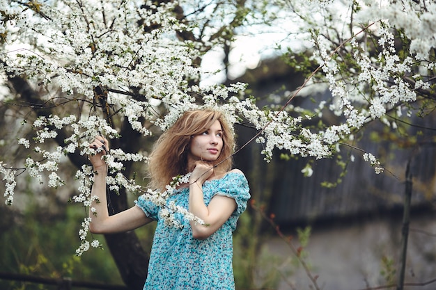 Beautiful girl walks in the lush garden dressed in a wreath