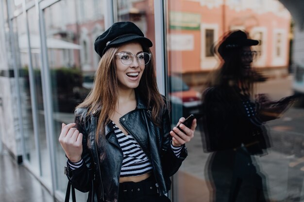 Beautiful girl walks on the street in black leather jacket after rain