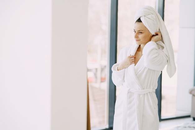 Foto gratuita bella ragazza in un accappatoio bianco a casa