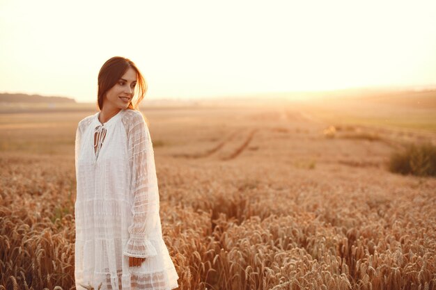 白いドレスを着た美しい少女。秋の麦畑の女性。