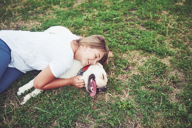 Bella ragazza con un bel cane in un parco sull'erba verde.