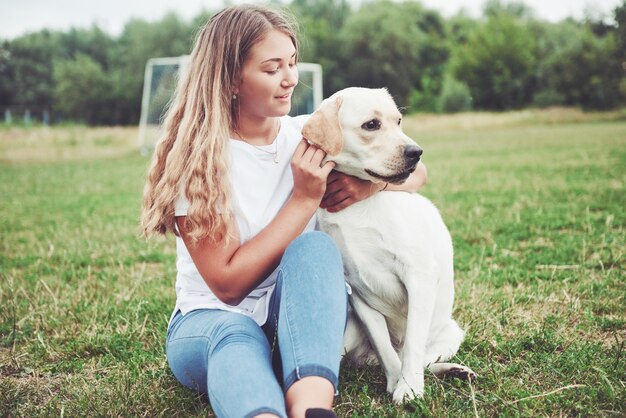 красивая девушка с красивой собакой в парке на зеленой траве.