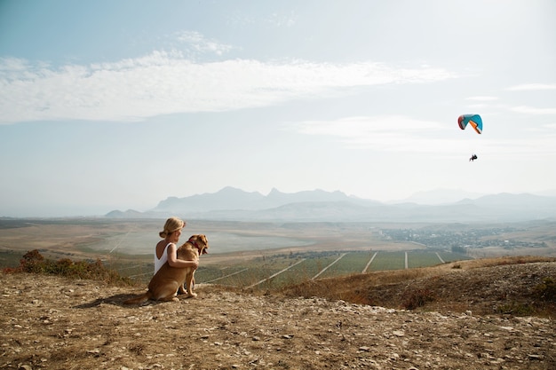 Красивая девушка с собакой на вершине горы