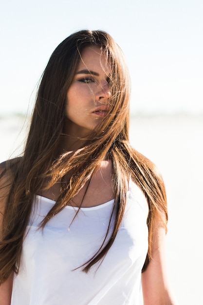 Foto gratuita bella ragazza con lunghi capelli brunetta e top bianco