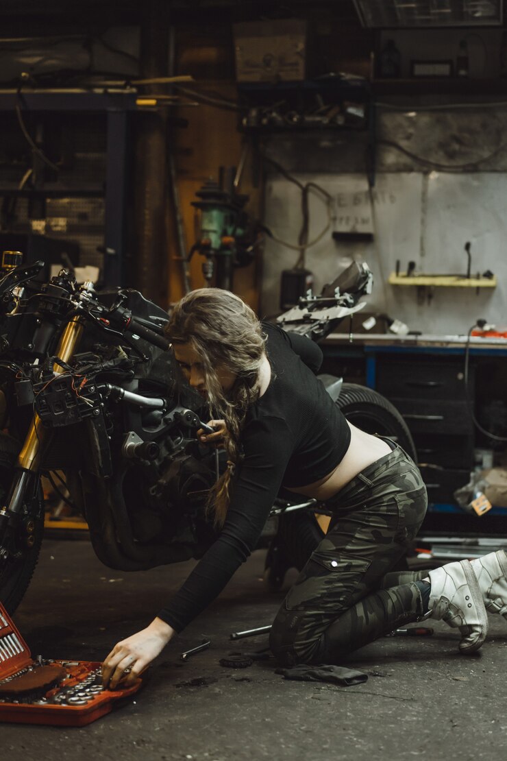 Free Photo beautiful girl with long hair in the garage repairing a motorcycle