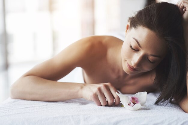 Beautiful girl with an orchid perfect skin near the big window.