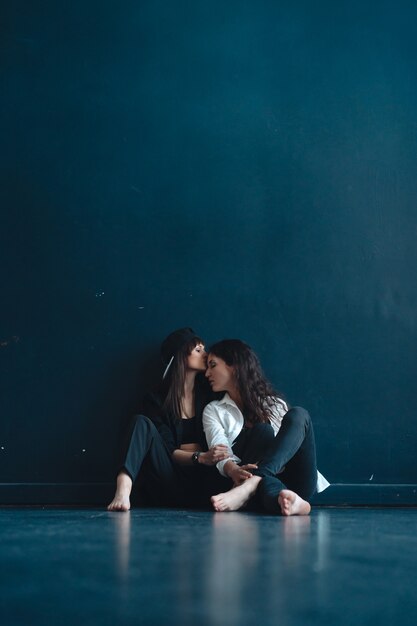 Beautiful girls sit by the wall and pose