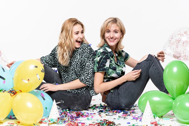 Beautiful girls  surrounded by confetti and balloons