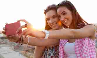 Free photo beautiful girls taking a selfie on the roof at sunset.