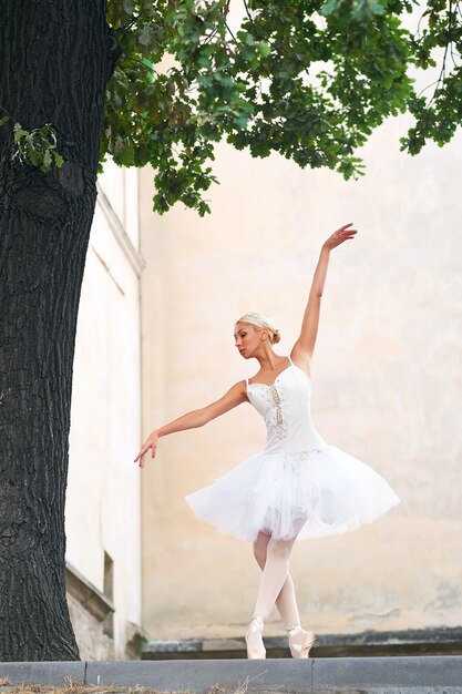 Beautiful graceful ballerina dancing on the streets of an old ci