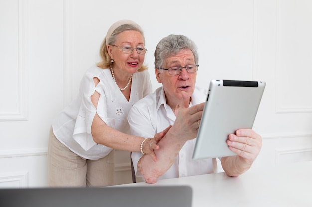 Пара красивая бабушка и дедушка учится использовать цифровое устройство