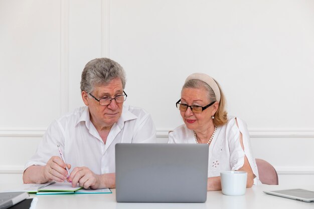 ノートパソコンの使い方を学ぶ美しい祖父母のカップル