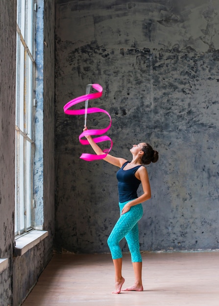 Beautiful gymnast woman dancing with pink ribbon