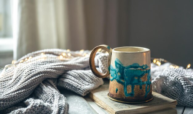 Beautiful handmade ceramic cup on a blurred background with a knitted element