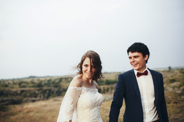 Beautiful and happy groom and bride walking together outdoors