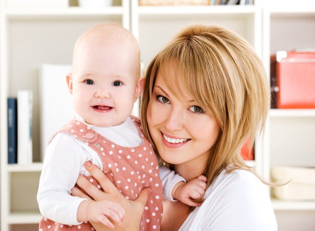 Beautiful happy mother holding  newborn baby on hands - Indoors