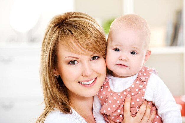 Beautiful happy mother holding  newborn baby on hands - Indoors