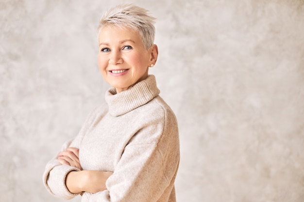 Free photo beautiful happy retired woman wearing cozy sweater and short hairdo