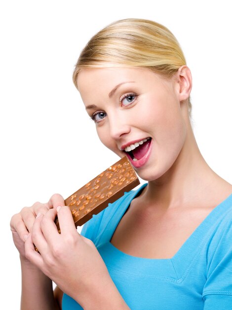 Beautiful happy woman eats the sweet black chocolate - isolated on white