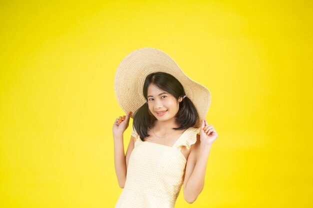 A beautiful, happy woman wearing a big hat showing cheerfulness on a yellow .