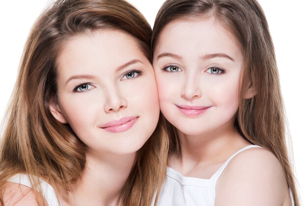 Beautiful and happy young mother with a small daughter 8 years embrace each other at studio