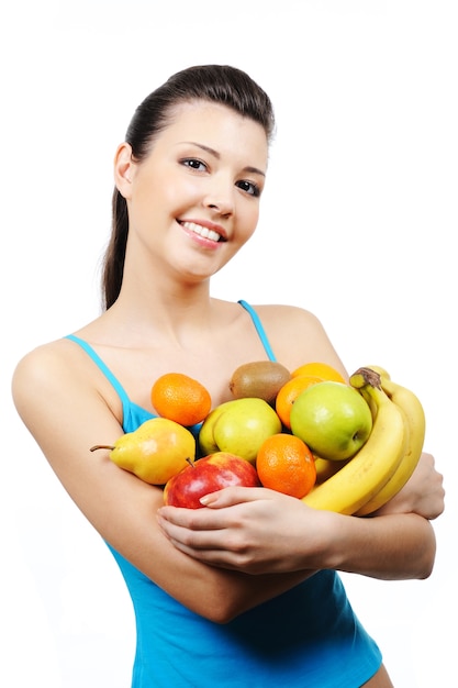 Beautiful happy young woman holding many fruits