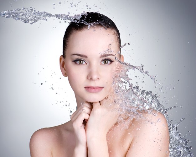 Beautiful healthy woman with clean fresh skin and splashes of water  - grey space