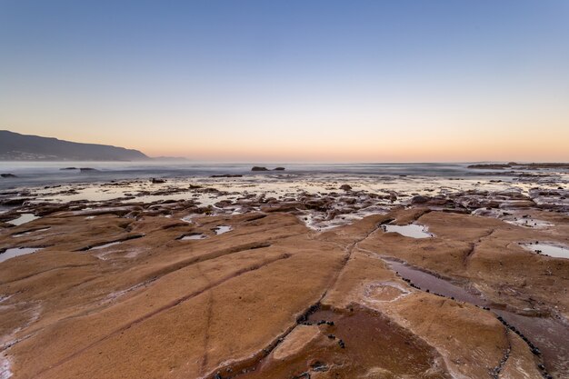 Beautiful high angle shot of the land near the body of the ocean water in the evening