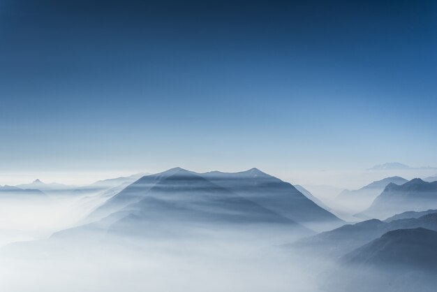 Красивые вершины покрыты туманом и облаками с ясным голубым небом