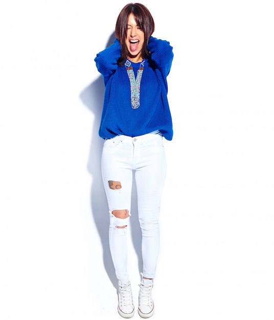 白い背景に分離されたカジュアルなスタイリッシュな夏の青いセーターで美しい流行に敏感なブルネットの女性モデル。彼女の舌を見せて