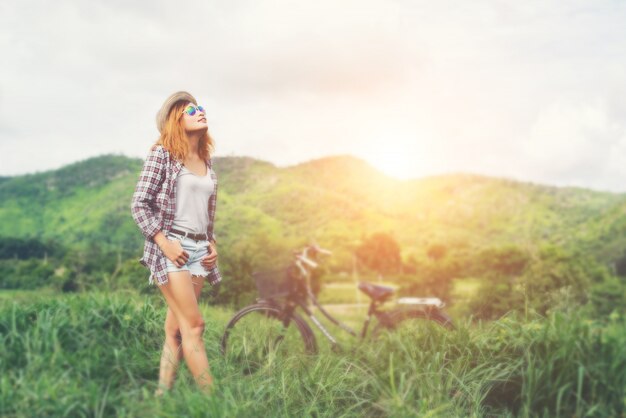 Beautiful hipster woman standing on a green meadow with nature a