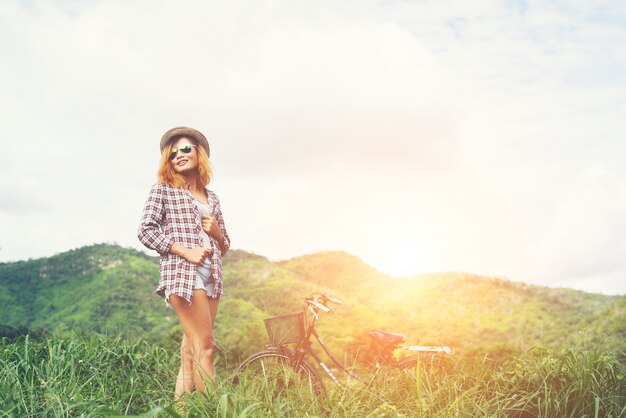 Beautiful hipster woman standing on a green meadow with nature a