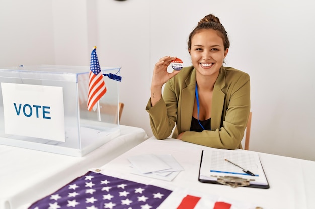 Free photo beautiful hispanic woman at political campaign by voting ballot looking positive and happy standing and smiling with a confident smile showing teeth