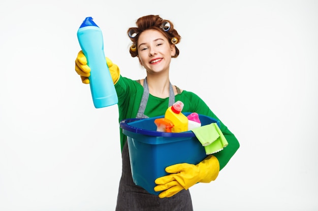 Beautiful housewife holds cleaning tools and shows bottle