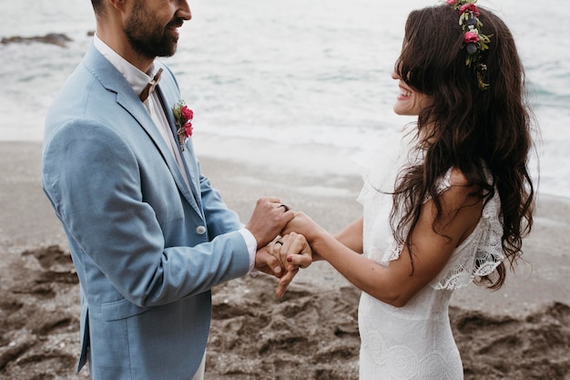 Free photo beautiful husband and wife posing on the beach at their wedding