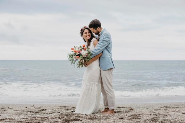 Free photo beautiful husband and wife posing on the beach