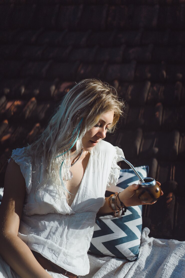 Free Photo beautiful indian hippie girl with long blond hair on the roof drinking mate tea. 
