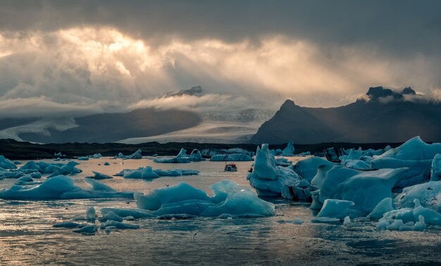 アイスランドの美しいヨークルスアゥルロゥン氷河ラグーン、暗い曇り空からの太陽光線