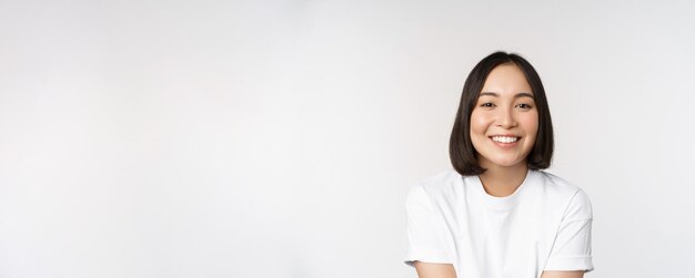 stuの上に白いTシャツに立っているカメラで素敵に見える白い歯を笑っている美しい韓国の女の子
