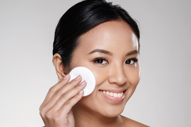 Beautiful lady cleaning her face with cotton pad